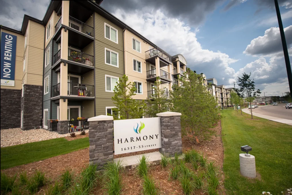 Apartment building with a Harmony sign and “Now Renting” banner