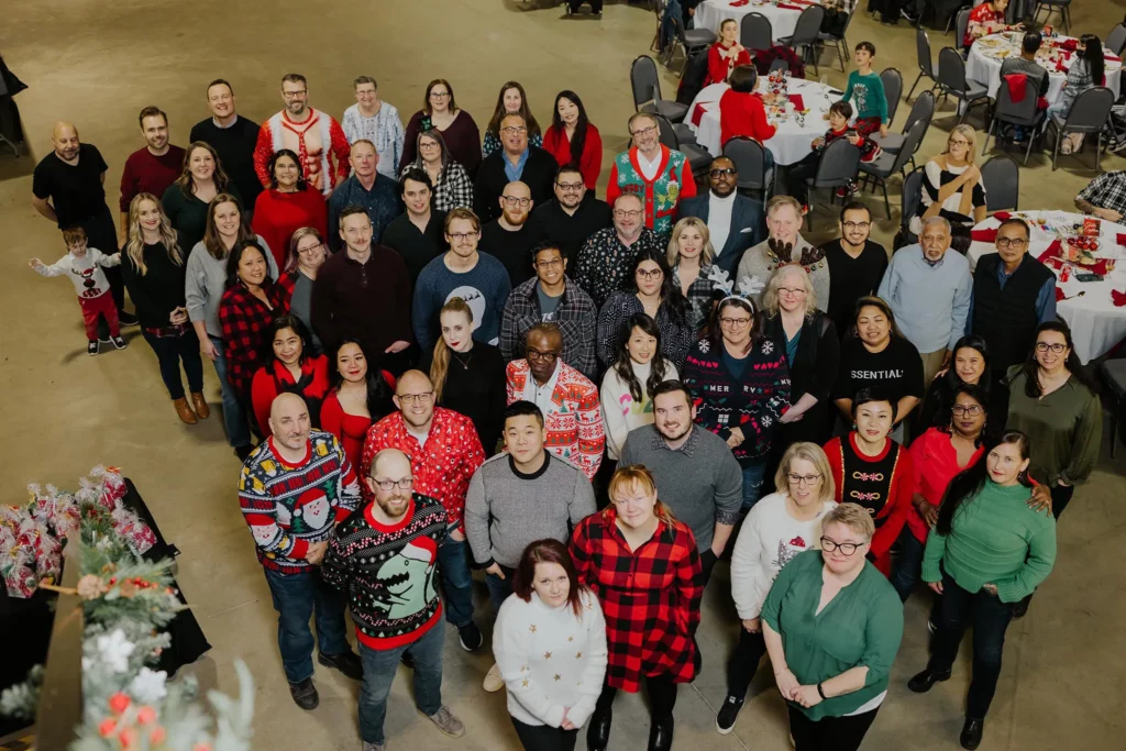 CDC team posing for a holiday party photo in a decorated banquet hall